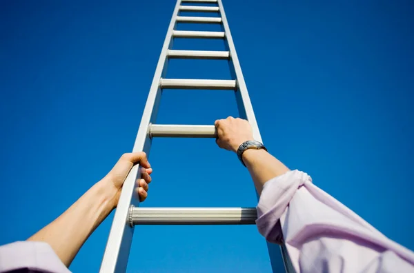 Low Angle Businessman Climbing Ladder Stock Photo