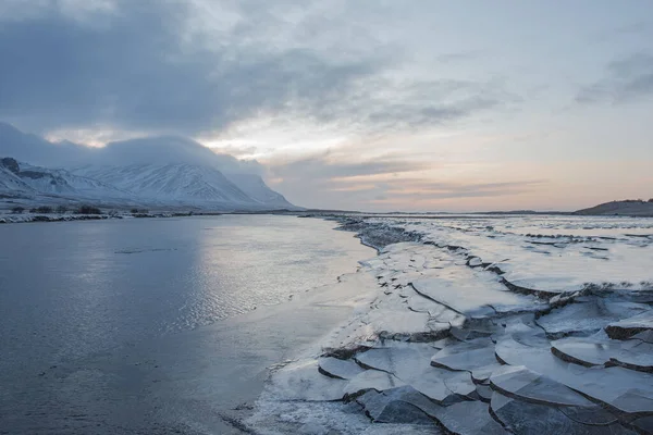 Arkasında Karla Kaplı Dağlar Olan Donmuş Bir Nehir Kıyısındaki Buz — Stok fotoğraf