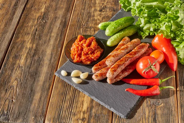 Gegrilde Varkensworstjes Met Verse Groenten Stenen Snijplank Houten Ondergrond Bovenaanzicht — Stockfoto