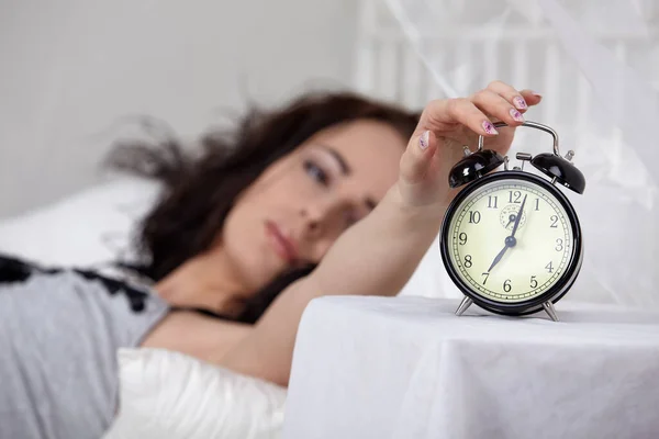 若い寝ている女性と自宅の寝室で目覚まし時計 目覚まし時計の選択的焦点 ロイヤリティフリーのストック写真