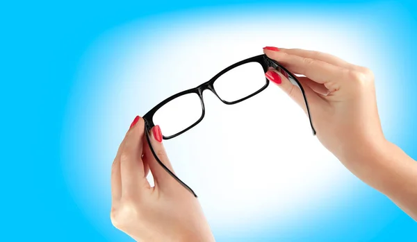 Weibliche Hand Mit Einer Schwarz Gerahmten Brille Auf Blauem Hintergrund — Stockfoto