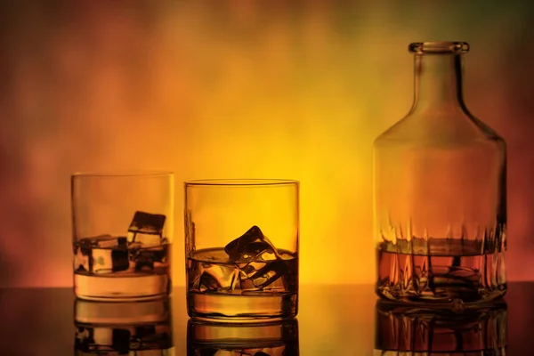 Fles Een Glas Whisky Met Ijs Oranje Achtergrond — Stockfoto