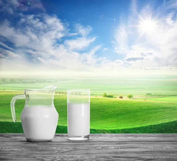 牛と山の牧草地の背景にデカンターとガラスのミルク — ストック写真