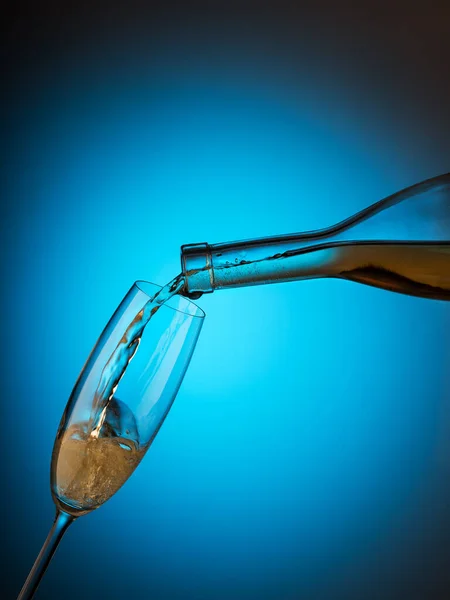 Champagne Viene Versato Bicchiere Dalla Bottiglia Sfondo Blu Concetto Celebrazione — Foto Stock