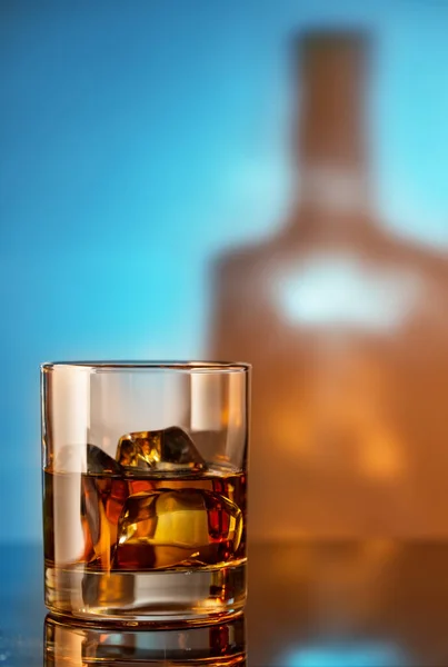 Ett Glas Whisky Med Mot Bakgrund Flaskan Blå Bakgrund — Stockfoto