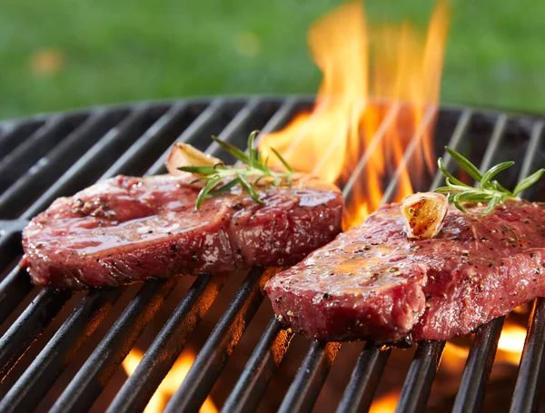 Nahaufnahme Von Zwei Saftigen Rindersteaks Mit Rosmarinkräutern Auf Brennendem Grill — Stockfoto