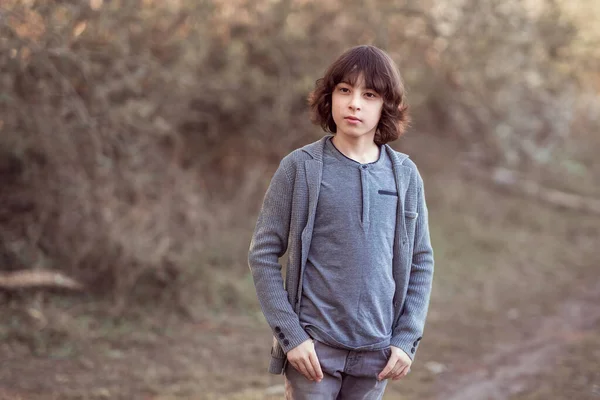 一个穿着牛仔裤和针织毛衣 以自然为背景的英俊时髦男孩的画像 — 图库照片