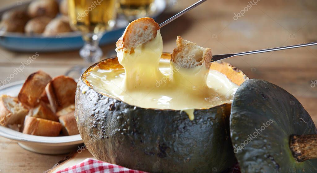 Rústica porción de fondue de queso en una corteza de calabaza hueca asada con baguette tostada
