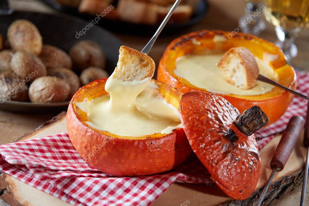 Porciones individuales de fondue de queso suizo servidas con trozos de baguette tostados para