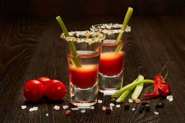 两杯带鸡尾酒的玻璃杯 血腥玛丽 香料和成熟的西红柿 深色木制底色 — 图库照片