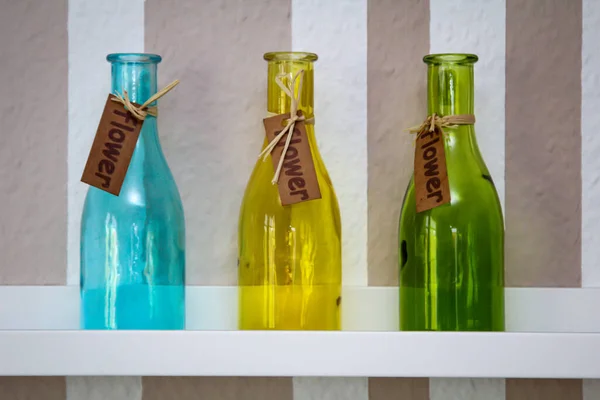 Три Разноцветные Стеклянные Бутылки Стоят Полке — стоковое фото