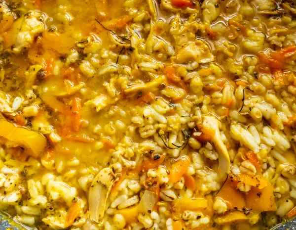 A thick and hearty homemade vegetable and chicken rice soup full of goodness, whole grain barley, peppers, chicken broth, seasonings, and chicken pieces ready to eat on a cold day.