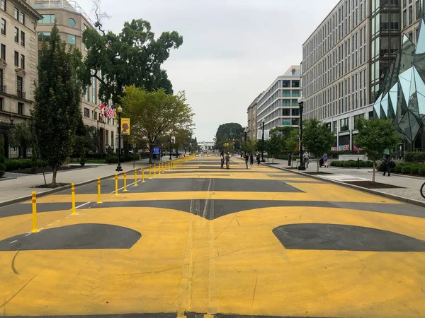 Long view of Black Lives Matter Plaza facing the White House. Full frame in natural light, pedestrians and overcast skies.