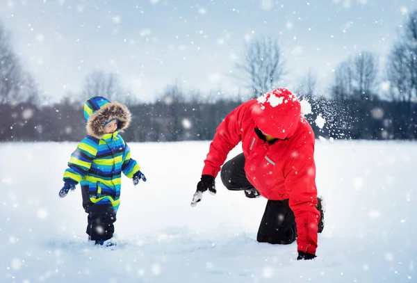 父亲和儿子在雪地里散步 穿着冬衣的孩子们和爸爸一起玩雪滑雪橇 — 图库照片