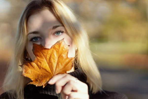 Mujer Joven Cubre Cara Con Una Hoja Arce Horizontalmente Imagen de stock