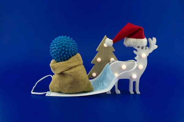크리스마스 사슴이 코로나 바이러스 선물을 의료용 마스크로 자루를 파란색 배경에만 — 스톡 사진