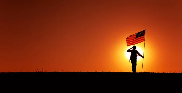 日没の背景に国旗を振って立っている間にアメリカ軍兵士 陸軍歩兵または海兵隊戦闘機のシルエット敬礼 軍の勝利と栄光 堕落した記憶 — ストック写真
