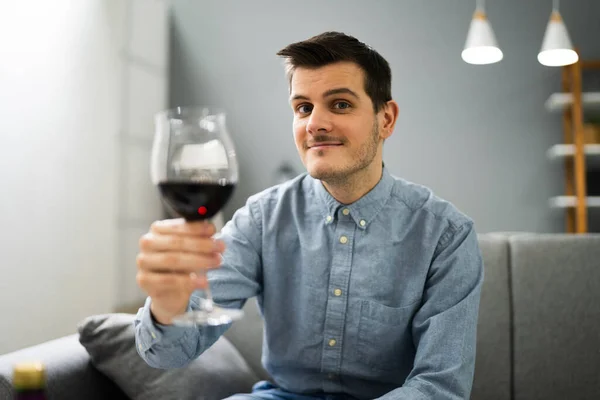 自宅でビデオ会議で赤ワインを飲む男 — ストック写真