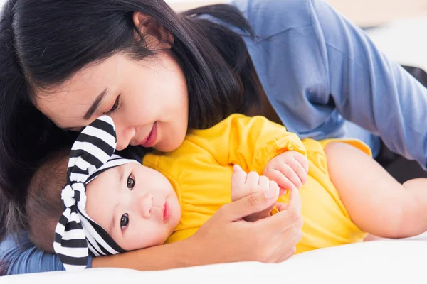 아시아인 어머니가 침대에서 태어난 아기에게 맞추는 엄마는 아기를 사랑하고 보험에 — 스톡 사진