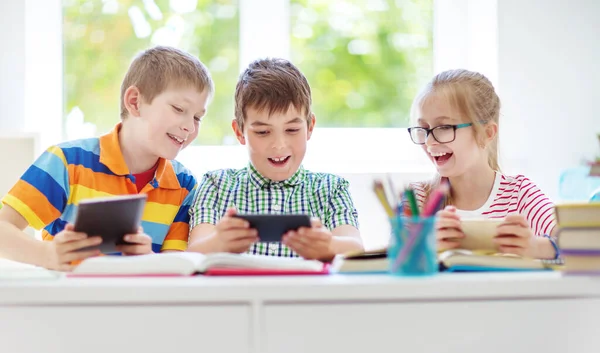 子供たちはスマートフォンで部屋に座っている 学校でサーフィンをしている生徒 ストック画像