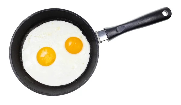 两个煎蛋在黑色煎锅中的顶部视图 与白色背景隔离 — 图库照片