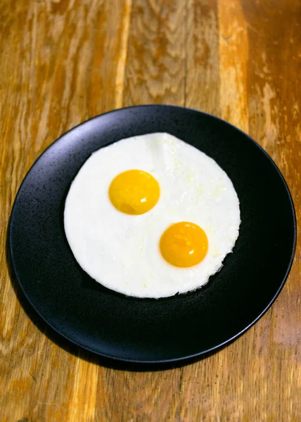 Два Яйца Черной Тарелке Деревянном Столе Домашней Кухне — стоковое фото