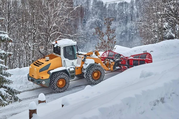 Snow plow machine clearing snow from roads after heavy snowfall in the Alps