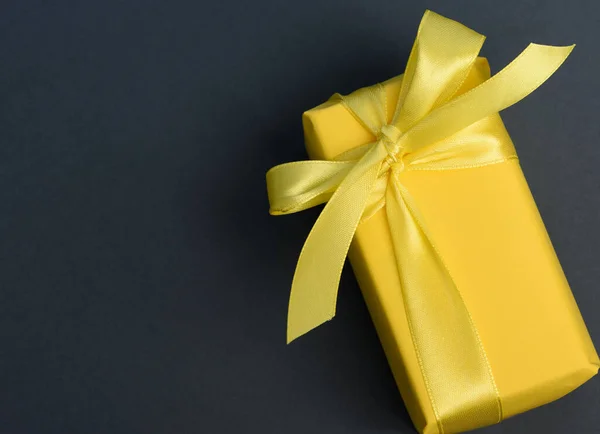 长方形盒子 礼物用黄纸包裹 用丝绸黄丝带捆扎 顶部视图 黑色背景 — 图库照片