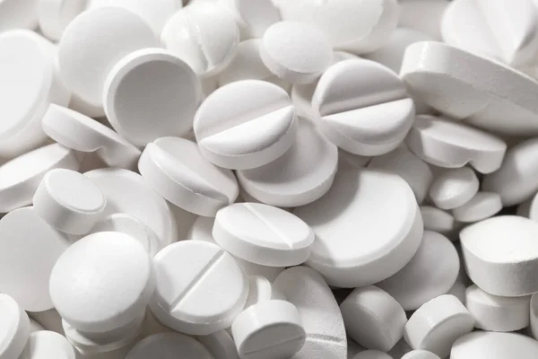 一排排的白色药丸 背景是一堆大小不一的药丸 — 图库照片