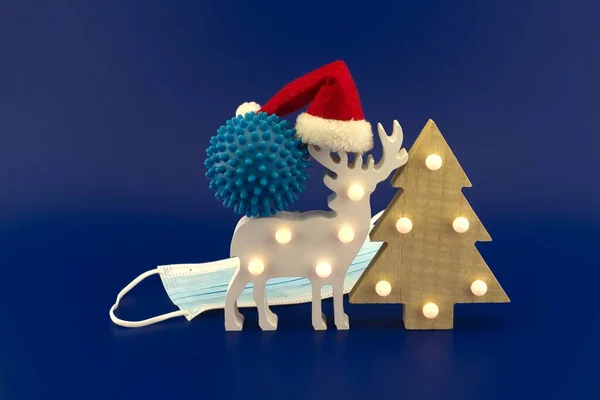 青いウイルス分子 赤いサンタの帽子 クリスマスツリー ギフトボックスと外科的顔マスクとクリスマスの概念はまだ生活の中ですべて青の背景に隔離 — ストック写真
