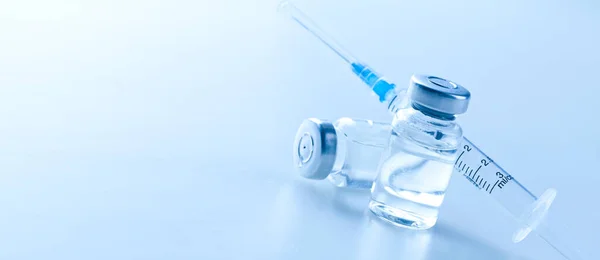 蓝色背景的医疗注射器和疫苗 — 图库照片