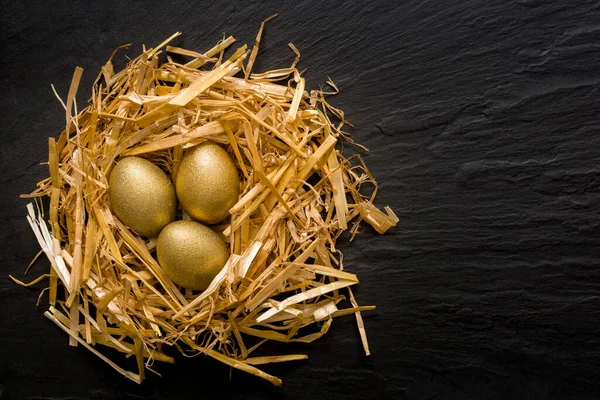 Three Golden Eggs Grassy Nest Black Slate Background Copyspace — Stock Photo, Image