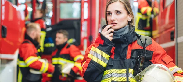 Piękna Strażaczka Hełmem Dłoni Stojąca Remizie — Zdjęcie stockowe