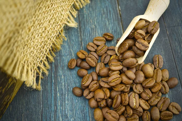 Granos Café Tostados Derramados Una Cucharada Madera Sobre Fondo Tela —  Fotos de Stock