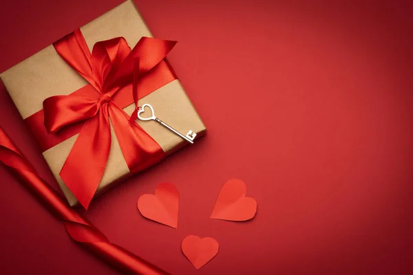 赤い絹の弓と赤い背景のテキスタイルハートの四角形の箱トップビューバレンタインデー — ストック写真