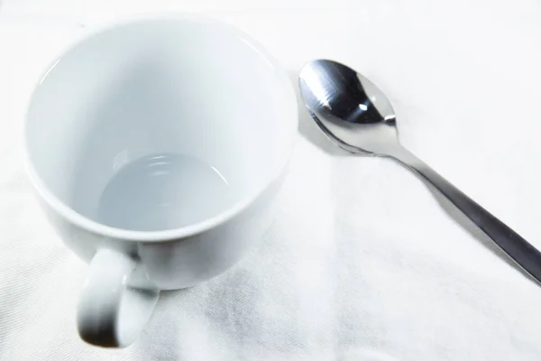 白ナプキンに大きく白い空のコーヒーカップ 銀攪拌スプーンの横にある — ストック写真