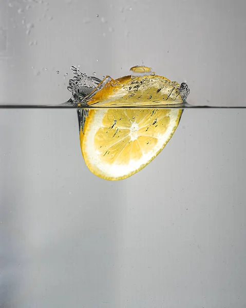 Een Plak Citroen Druppels Met Een Plons Helder Water — Stockfoto