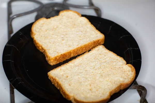 Kaksi Viipaletta Leipää Mustalla Lautasella Liedellä — kuvapankkivalokuva