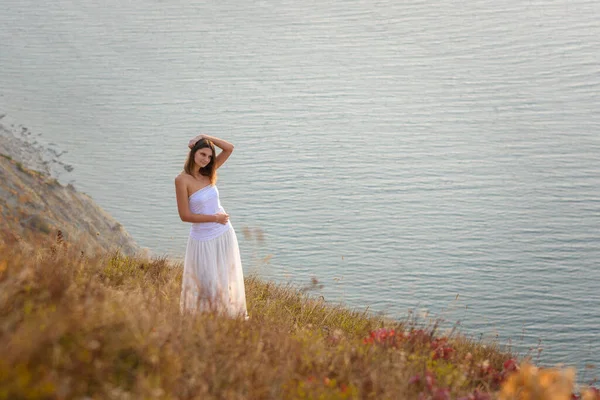 美しい背の高い細い女の子が海のそばの丘の上に立っている — ストック写真
