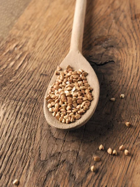 在木制厨房桌子上的木制勺子上放有机荞麦 上面有文字 健康食品的概念 — 图库照片