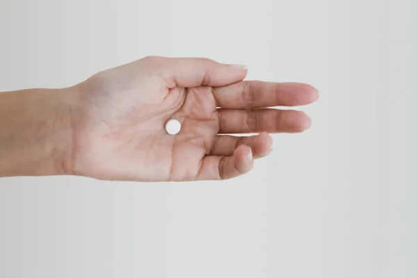 Χέρι Κρατώντας Ένα Λευκό Χάπι Ένα Ελαφρύ Φόντο — Φωτογραφία Αρχείου