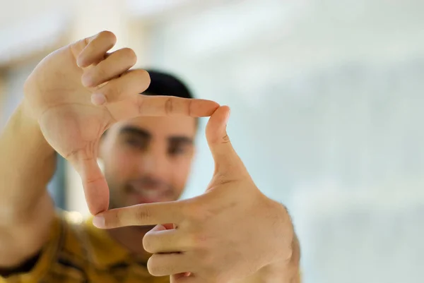 Man Die Door Vingers Kijkt Een Wazige Achtergrond — Stockfoto