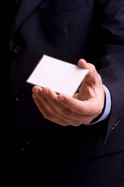 黒の背景の白いカードを持っているビジネスマンは — ストック写真