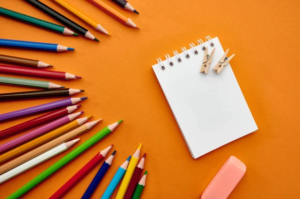 カラフルな鉛筆やメモ帳 オレンジの背景のセット 事務用品 学校用品又は教育用品 筆記用具及び図面用具 — ストック写真