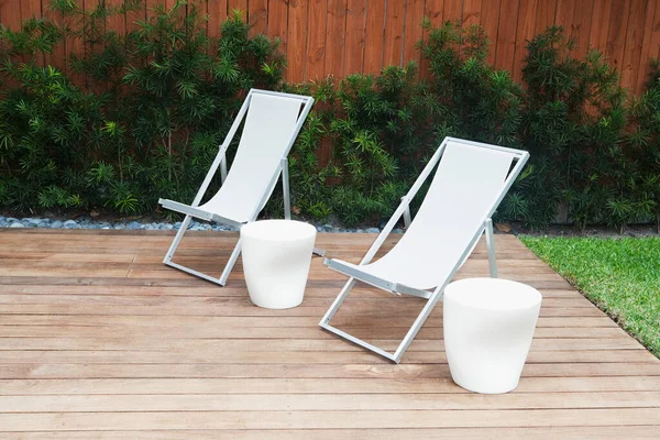 Chairs with stools on the floorboard in a garden