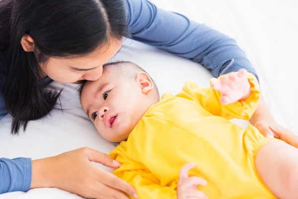 아시아인 어머니가 침대에서 태어난 아기에게 맞추는 엄마는 아기를 사랑하고 보험에 — 스톡 사진