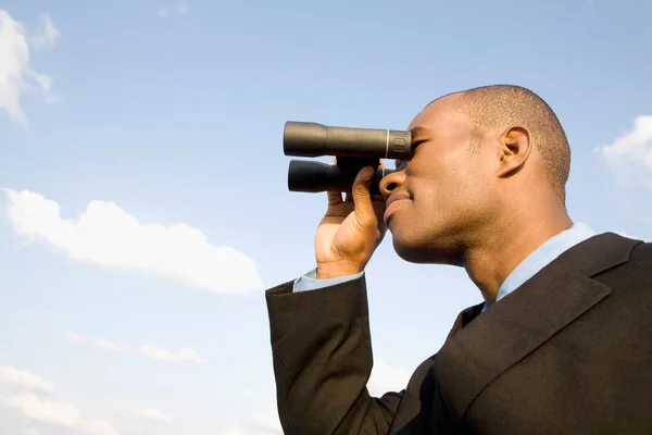 young businessman with binoculars in sky