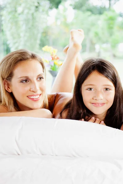 幸せな母親と娘が家のベッドに横になり — ストック写真