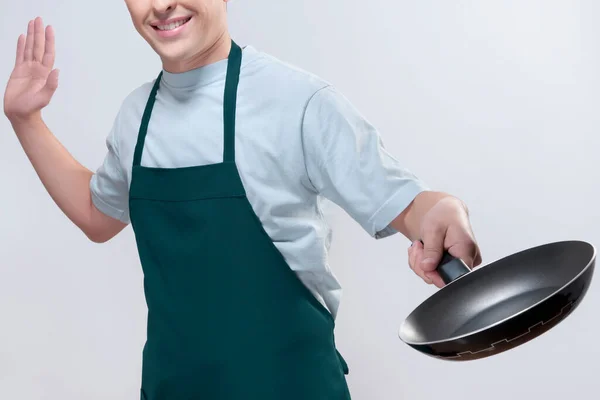 围裙上的年轻厨师拿着一个有勺子的盘子 背景是白色的 — 图库照片