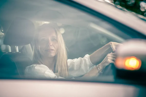 Pretty midle aged woman at the steering wheel of her car commuting to work